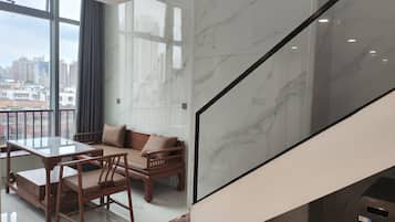 Un interior moderno con comedor, sofá y vistas a la ciudad a través de amplias ventanas.