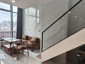 A modern interior with a dining area, a sofa, and a view of the city through large windows. - Healing Warm Home (Shen Zhen Shi)