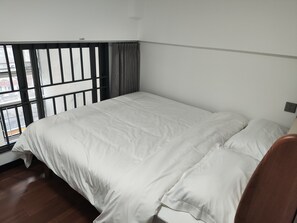 Una habitación con cama, ventana con persianas y vista a la calle.