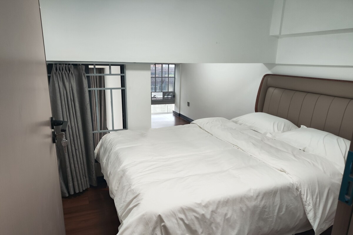 A bedroom with a bed, a window with curtains, and a view of the outdoors.