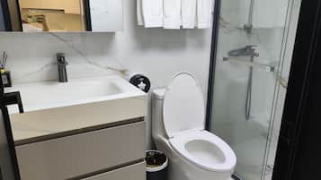 Un baño moderno con inodoro, lavabo y zona de ducha.