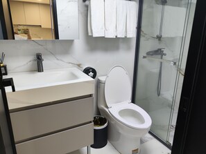 Un baño moderno con inodoro, lavabo y zona de ducha.