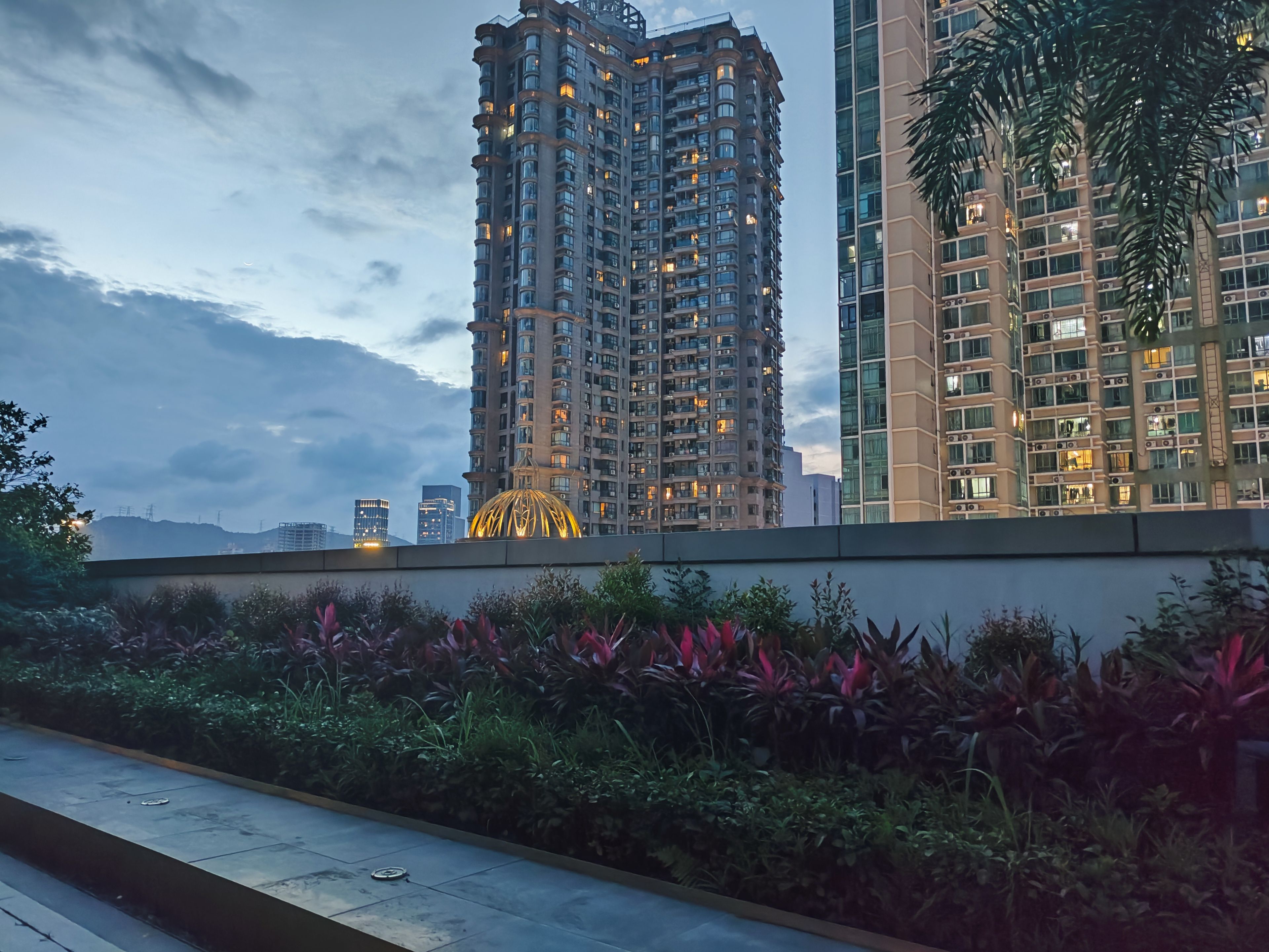 Un edificio de gran altura con varios balcones y un jardín bien cuidado al frente.
