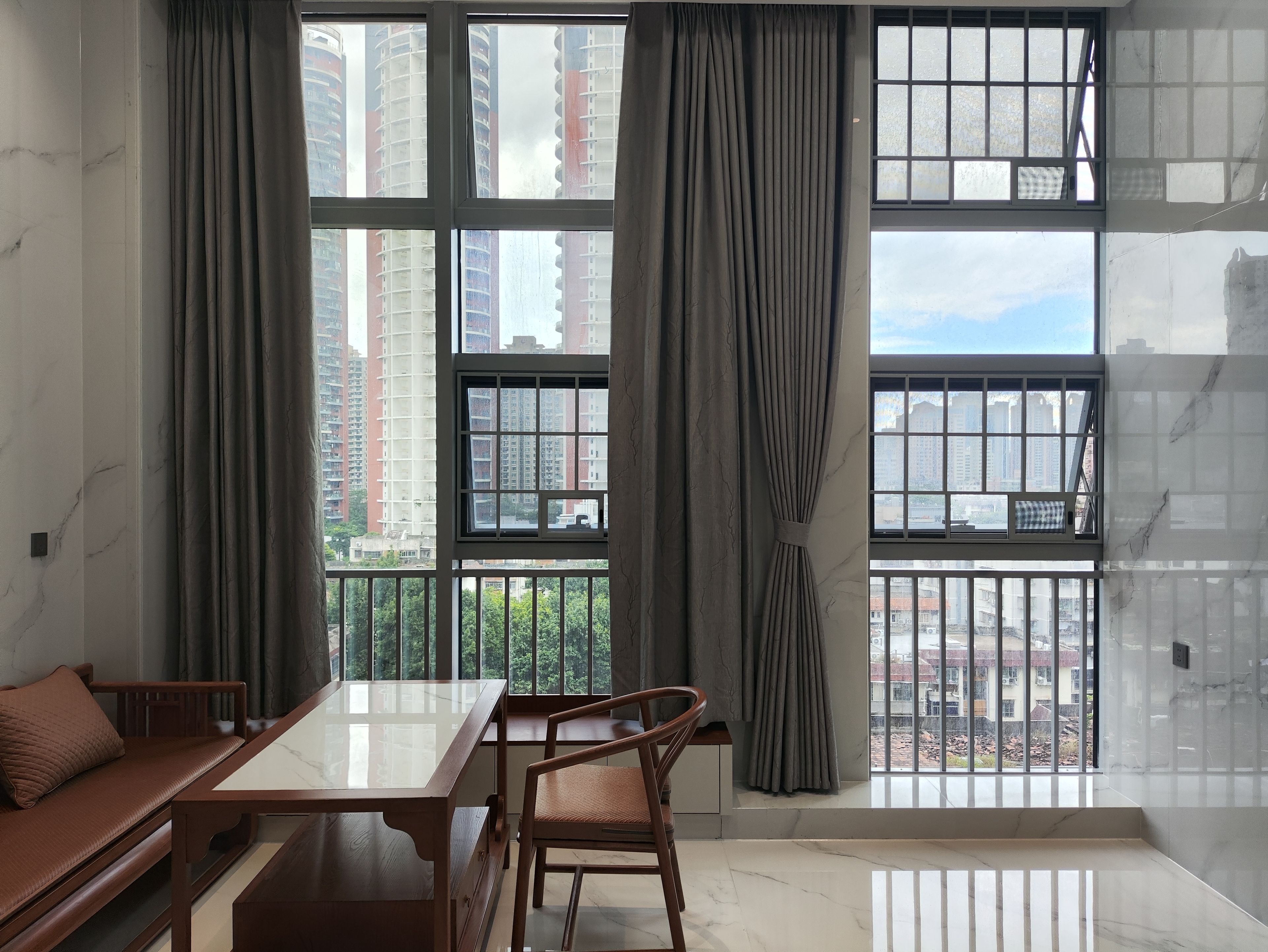 Una habitación con un ventanal grande, una mesa de madera, un sofá y una silla.