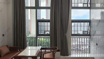 Una habitación con un ventanal grande, una mesa de madera, un sofá y una silla.