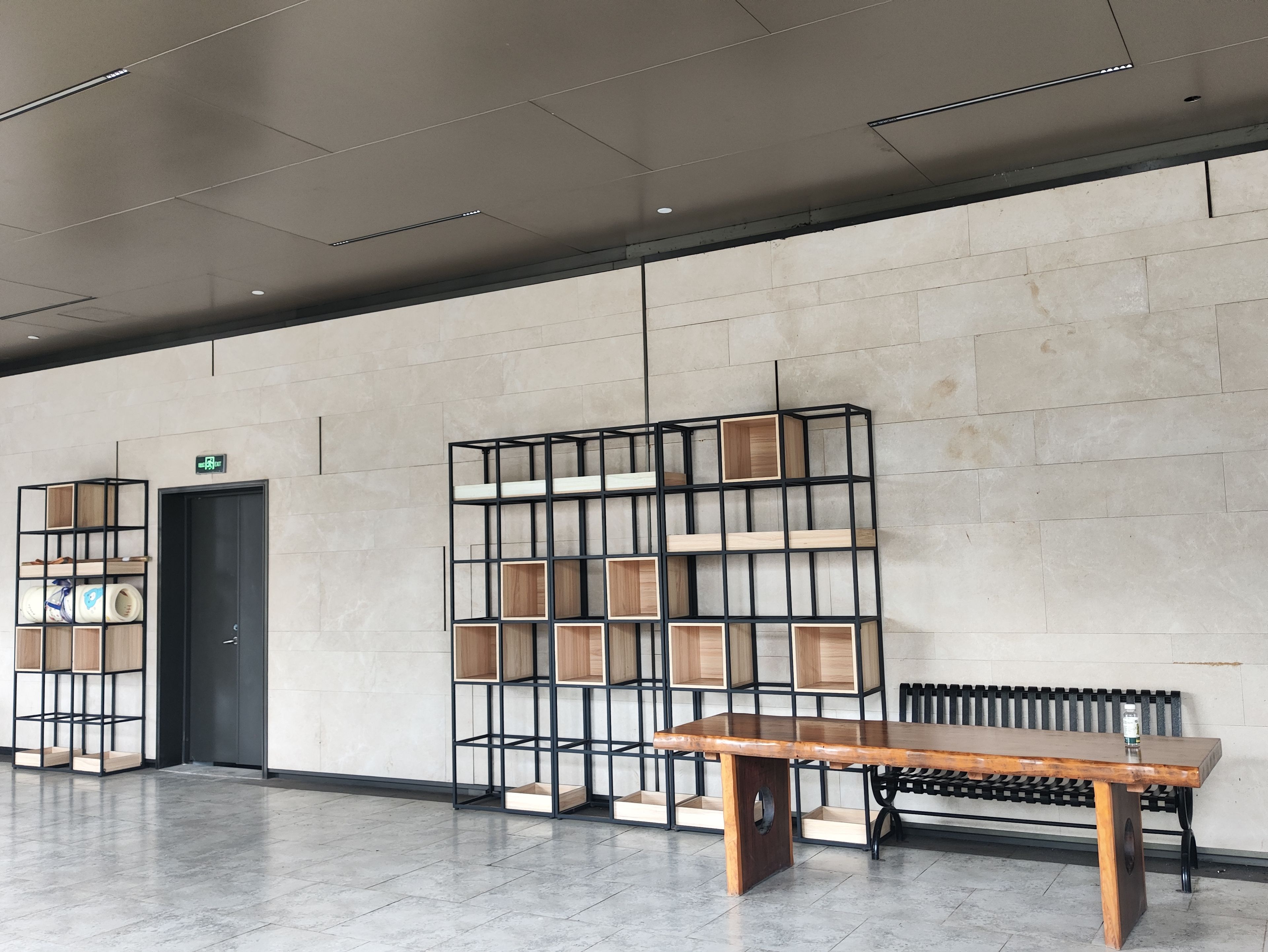 A modern interior with a wooden bench, metal shelving units, and a tiled floor.