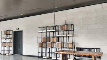 A modern interior with a wooden bench, metal shelving units, and a tiled floor.