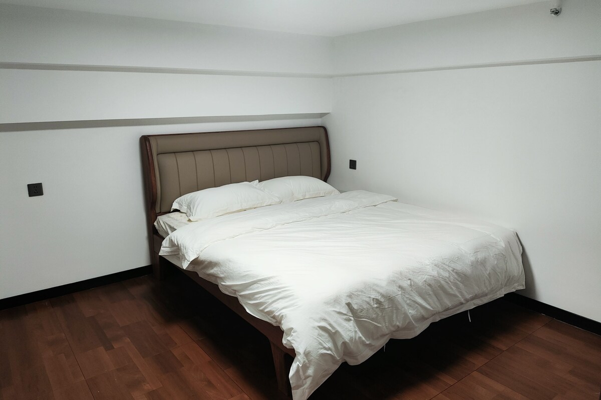 A single bed with a wooden headboard in a room with white walls and wooden flooring.