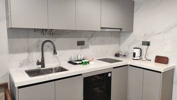 A modern kitchen with grey cabinets, a stainless steel sink, a built-in oven, and a coffee maker.