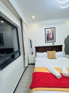 A hotel room with a bed, a window, a wall-mounted picture, and a ceiling light. - Elagant 2BR in lavington/kilimani/kileleshwa w/pool gym near malls central place (Nairobi)