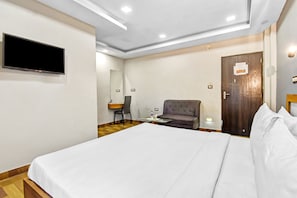 Een hotelkamer met een bed, een bureau, een stoel, een televisie en een deur.
