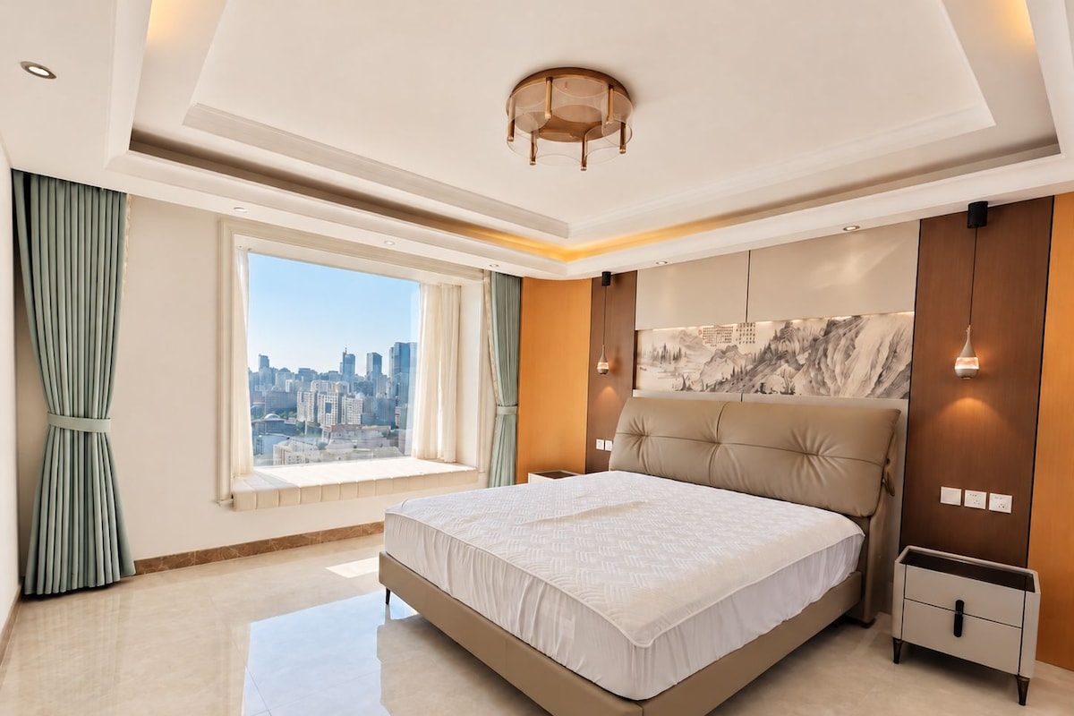 Un dormitorio moderno con una cama grande, vista a la ciudad y un elemento decorativo en la pared.