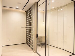 A modern office space with a work pod, glass walls, and a chair. - Rentico | 1BR Marina Waterfront | Pool & Cinema (Dubai)