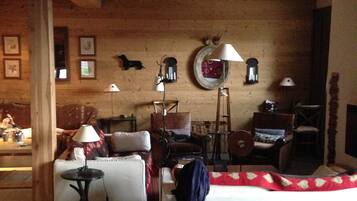 A cozy room with a wooden ceiling, a sofa, a table with a lamp, and a bed.