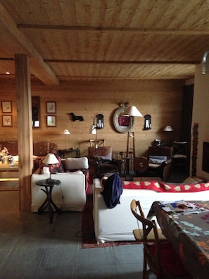Ett mysigt rum med ett träpanelat tak, en soffa, ett bord med en lampa och en säng.
