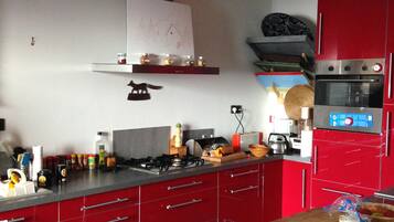 A kitchen with red cabinets, a gas stove, and a microwave.