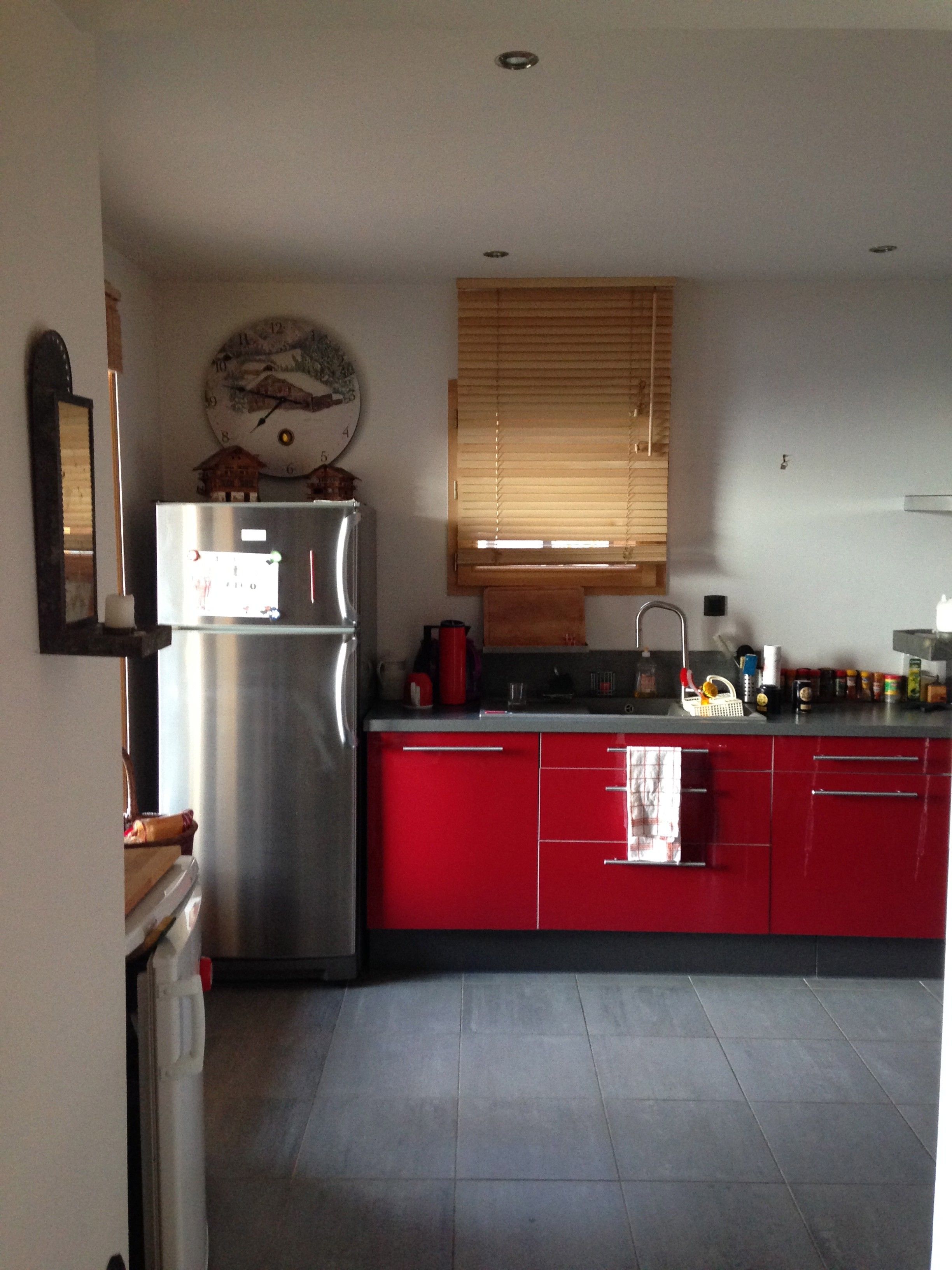 Una cocina con refrigerador, lavamanos y armarios rojos.