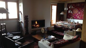 A cozy living room with a fireplace, a sofa, a dining table, and a television.