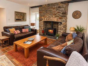 A cozy living room with a stone fireplace, leather sofas, and a wooden coffee table. - Coastal Cottage - Beach - Parking - Pet friendly (Broad Haven)