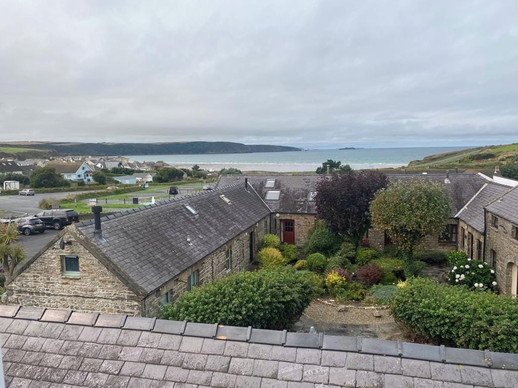A coastal residential area with stone buildings, a view of the sea, and a paved road.