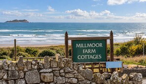 A sign for Millmoor Farm Cottages with a view of the ocean and distant islands. - Coastal Cottage - Beach - Parking - Pet friendly (Broad Haven)