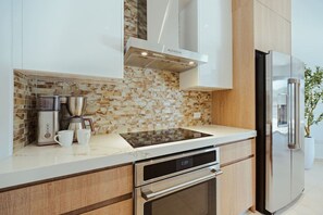 A modern kitchen with a built-in stove, oven, and refrigerator. - Walishali ONE17 • Chic 1BR Condo w/ Resort Access (Noord)