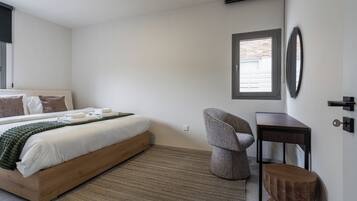 A bedroom with a bed, a chair, a desk, and a window.