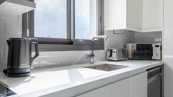 A modern kitchen with a stainless steel kettle, a toaster, and a microwave on the counter.