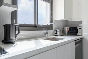 Una cocina moderna con tetera de acero inoxidable, tostadora y microondas sobre la encimera.