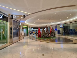 Interior de um shopping com decoração de Natal, um aviso indicando 'Saída para o Estacionamento Mayflower St.' e uma loja BDO.