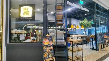 Eine Bäckerei mit einem Schild, das 'dein tägliches Brot' verkündet, und einer Speisekarte vor der Tür.