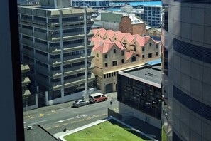A high-rise building with a parking lot and a road with vehicles. - Luxury City Retreat with Balcony Pool and Gym (Auckland)