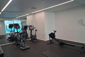 Une salle de sport équipée de divers appareils d’exercice, notamment des tapis de course, des vélos d’appartement et un appareil d’escalier.