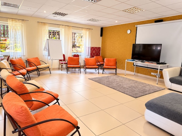A conference room with a whiteboard, a television, and several orange chairs. - Renessans Rehabilitation Center (Pokrzywna)