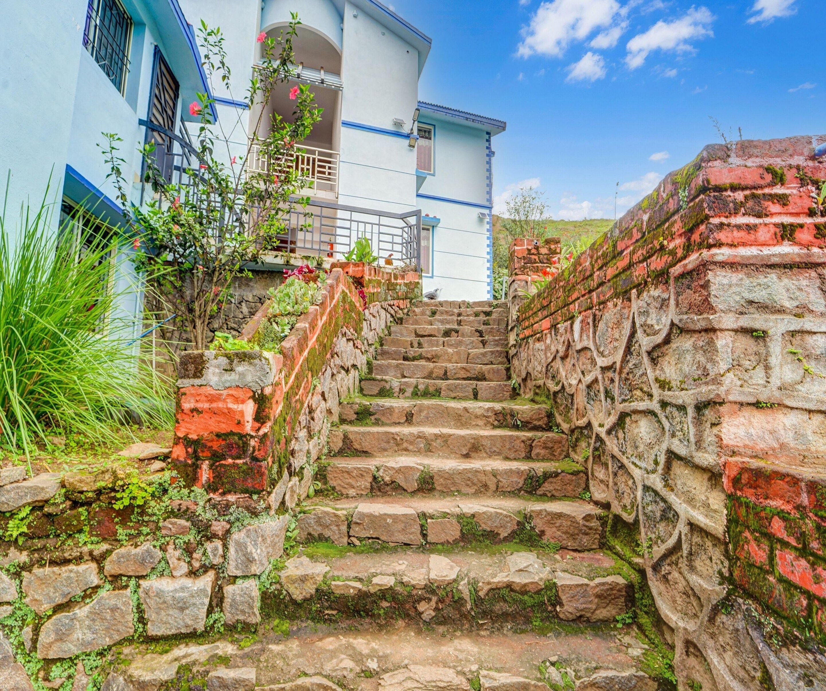 Una escalera de piedra conduce a un edificio blanco con detalles azules y un balcón.