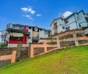 Un hôtel reconnaissable à son grand panneau « HÔTEL », à l’escalier menant à l’entrée et à son mur de soutènement en pierre.