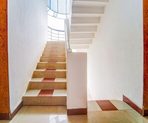 Un escalier avec une rampe, menant à un palier surmonté d’une verrière.