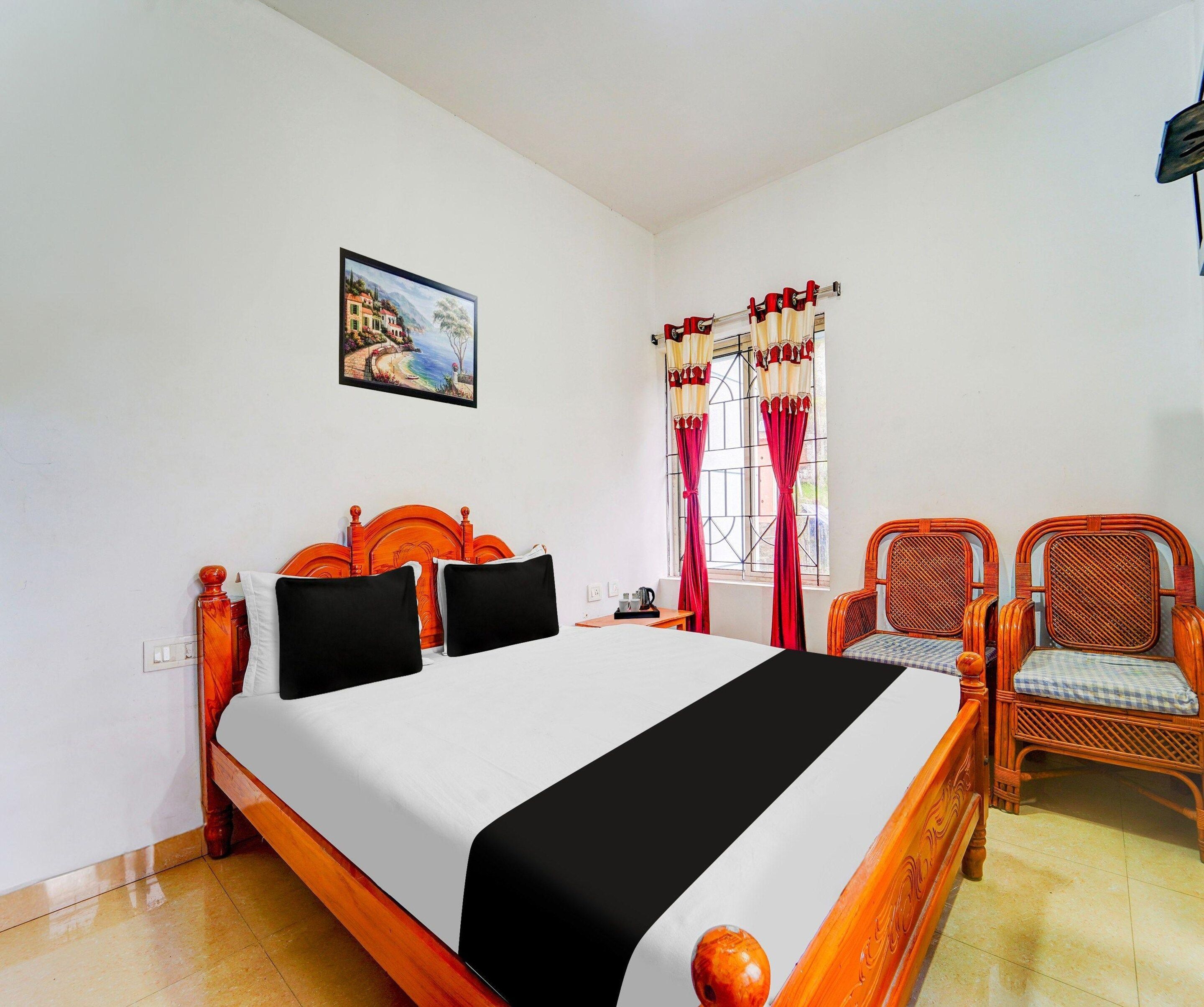 Un dormitorio con cama, una silla, un cuadro y una ventana con cortinas.
