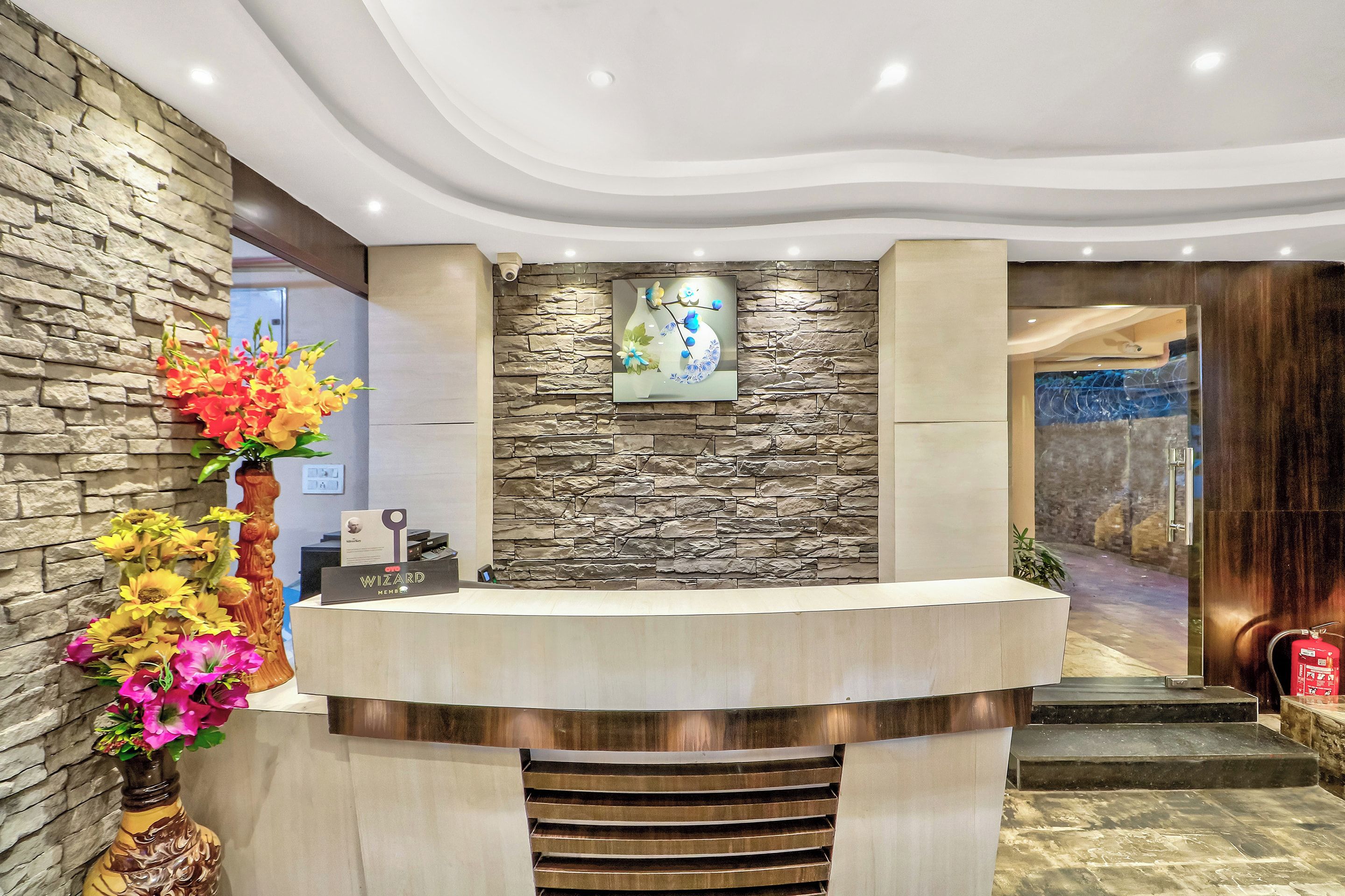 Zona de recepción con pared de piedra, mostrador de recepción y un elemento decorativo en la pared.