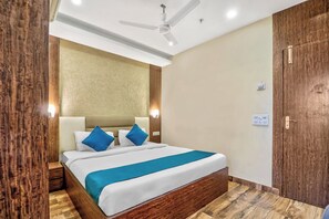 Ein Hotelzimmer mit einem Bett, einem Holz-Kopfteil, Nachttischen, einem Deckenventilator und einer Tür.