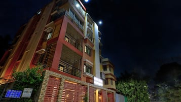 Un hotel de varios pisos con una entrada destacada, balcones y un letrero que indica que es un hotel.