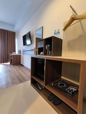 A modern hotel room with a wooden entertainment unit, a flat-screen TV, and a coffee machine. - Wisma SIDAPORE JD (Banggai)