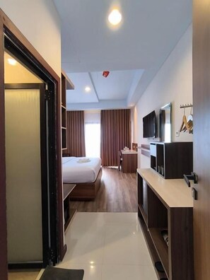 A hotel room with a bed, a desk, a television, and a wardrobe. - Wisma SIDAPORE JD (Banggai)