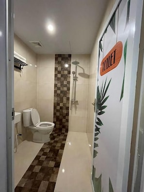 A bathroom with a toilet, shower, and a checkered floor pattern. - Wisma SIDAPORE JD (Banggai)