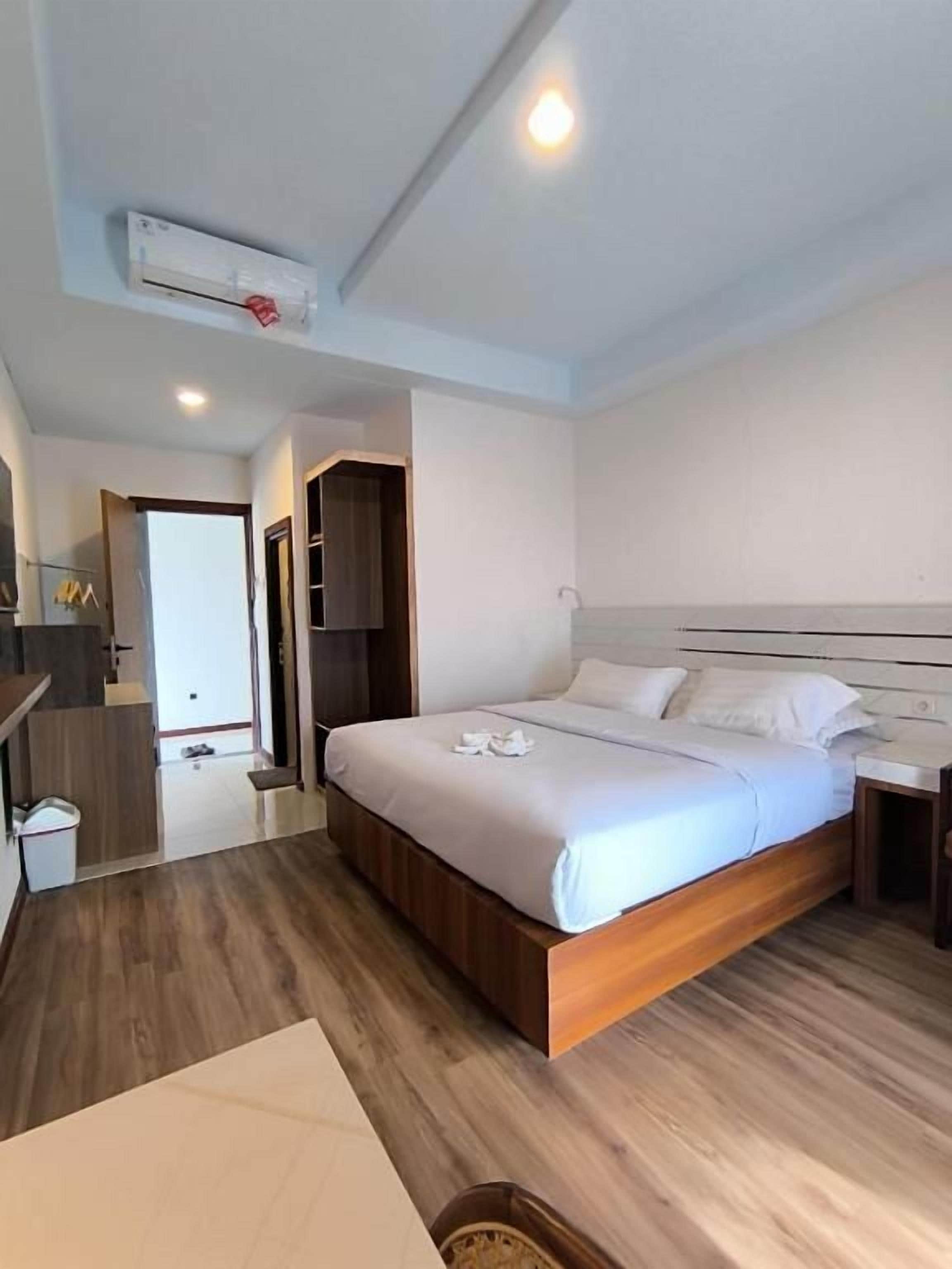 Quarto de hotel moderno com cama de madeira, mesa de cabeceira e guarda-roupa embutido.