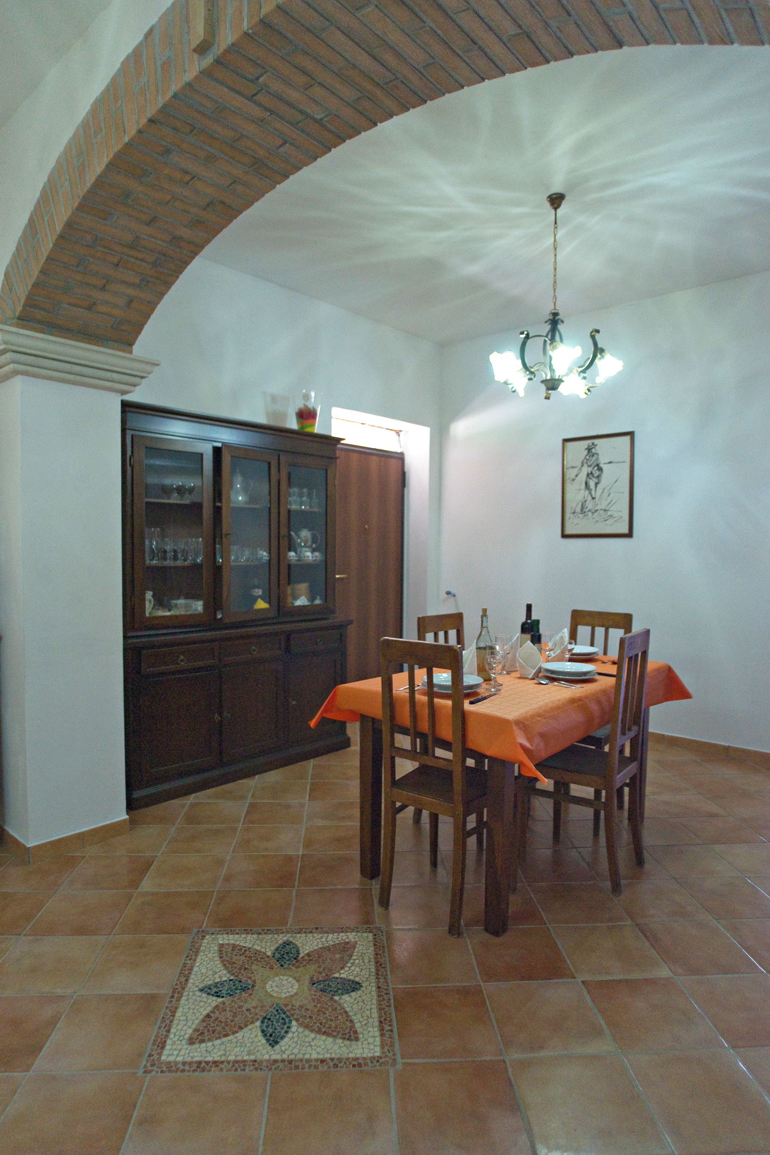 A dining area with a table set for four, a cabinet with glass doors, and a patterned floor.