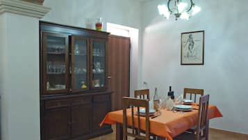 A dining area with a table set for four, a cabinet with glass doors, and a patterned floor.
