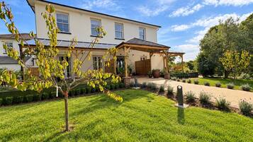 A two-story house with a covered patio, a well-maintained lawn, and a garden with various plants.