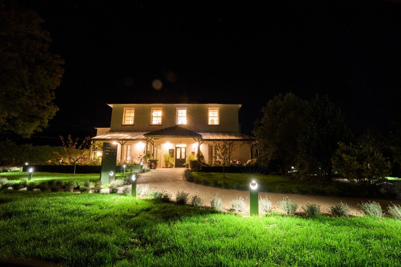 Uma casa de dois andares com entrada bem iluminada e um caminho que leva à porta da frente.