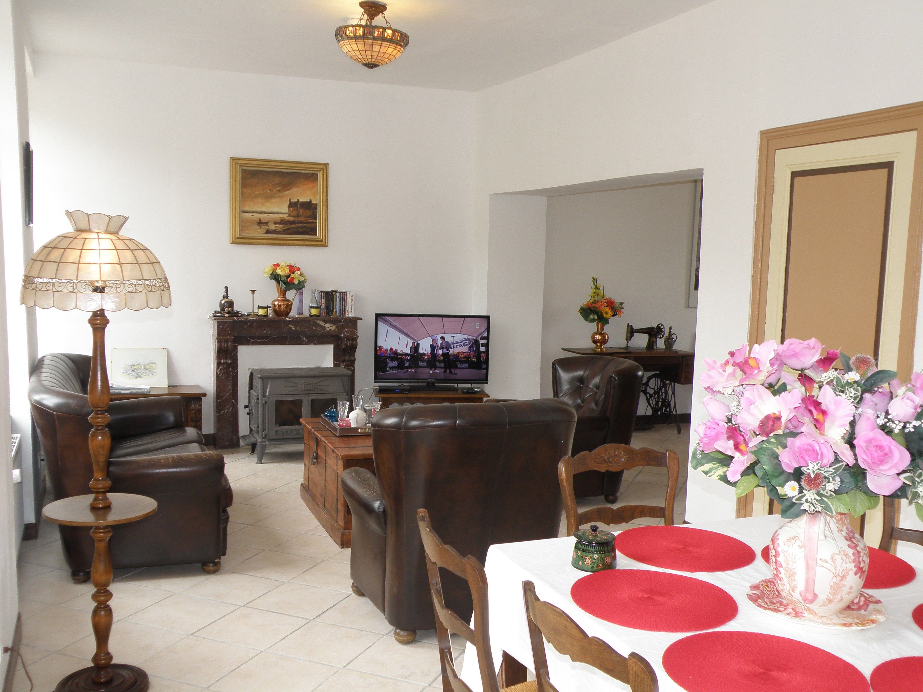 Un salon doté d’une cheminée, d’un téléviseur, de meubles en cuir et d’un coin repas avec une table mise pour deux personnes.